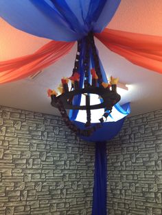 a blue pole with red and orange streamers hanging from it's sides in front of a wall