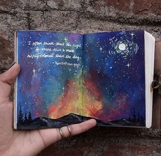 someone is holding an open book in their left hand and the pages are painted with watercolors