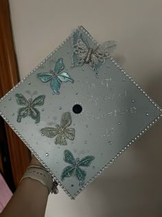 a hand holding a graduation cap decorated with butterflies