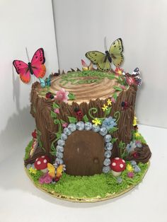 there is a cake that looks like a tree stump with flowers and butterflies on it