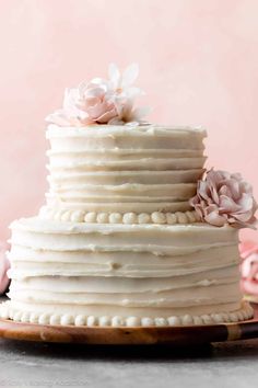 a close up of a cake with white frosting and pink flowers on the top