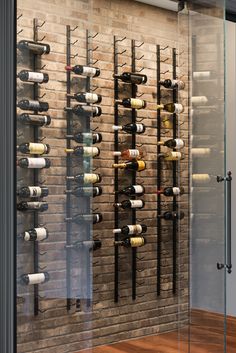 a wine rack with many bottles on it in front of a brick wall and wooden floor