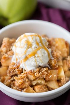 an apple crisp with ice cream and caramel drizzle in a white bowl