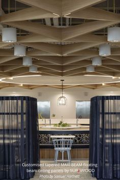 an open kitchen and dining room area with blue curtains on the ceiling, white counter tops and bar stools