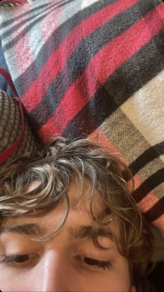 a young man laying on top of a plaid blanket