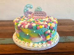 a multicolored decorated cake sitting on top of a wooden table