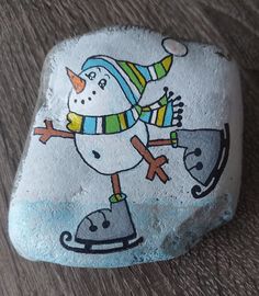 a painted rock with a snowman skating on it