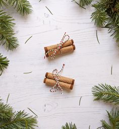 two cinnamon sticks tied with twine on top of pine branches and decorated with candy canes