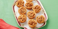 a platter filled with mini pies sitting on top of a green tablecloth