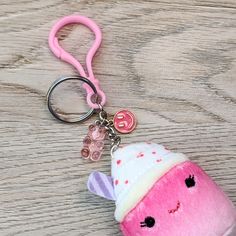 a pink stuffed animal keychain with a white and pink hat on it's head