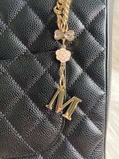 a close up of a purse with a chain attached to the handle and letter m on it