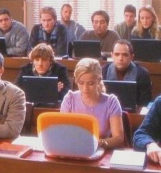 a group of people sitting at desks with laptop computers in front of their faces