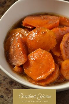 a white bowl filled with cooked carrots on top of a table