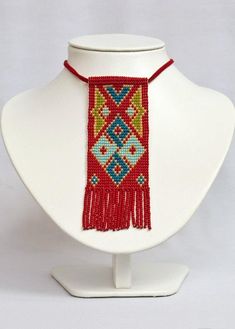 a white mannequin with a red beaded necklace on it's neck