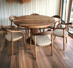 a round wooden table with six chairs around it in a room that has wood flooring