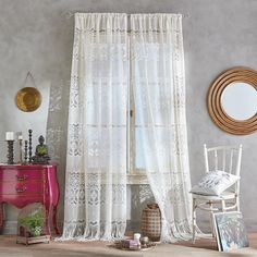 a living room with a pink dresser and white lace curtains on the windowsills