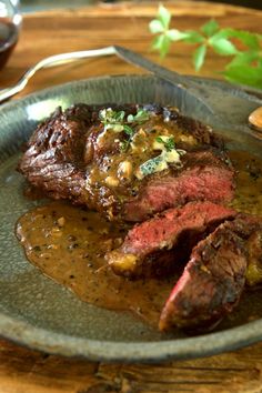 a steak with gravy on a plate next to a fork and spoons