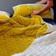 a person is unpacking two yellow pillows on a bed