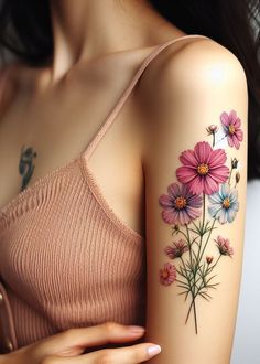 a woman's arm with pink and blue flowers tattooed on the left side of her arm