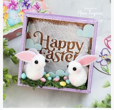 two bunny figurines sitting in an easter box with the word happy easter painted on it