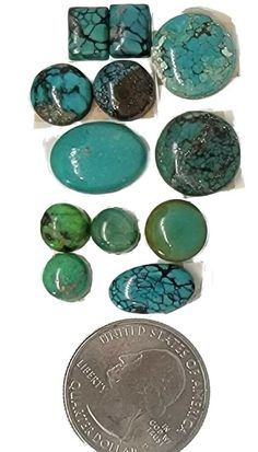 some turquoise and green stones next to a penny