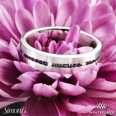 two wedding rings sitting on top of a purple flower