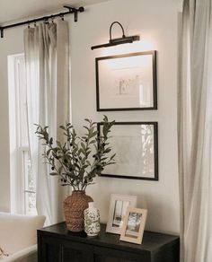 a black and white living room with pictures on the wall, plants in vases