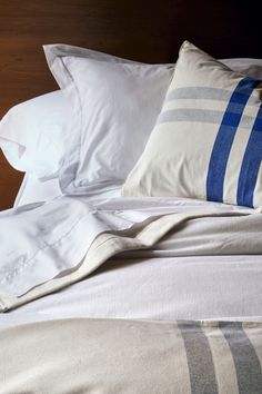 an unmade bed with white and blue pillows