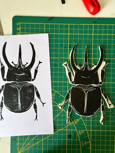 two black and white bugs are on a cutting board next to a pair of scissors