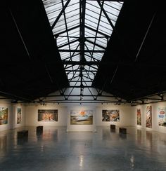 an empty room with paintings on the walls and a skylight in the ceiling above