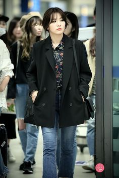 a woman in black jacket and jeans walking down the street