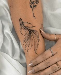 a woman's arm with a tattoo on it that has a goldfish and flowers