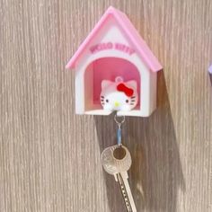 a hello kitty keychain hanging from the side of a wall with a house shaped like a cat