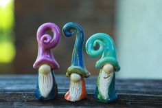 three small colorful figurines sitting on top of a wooden table next to each other