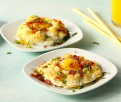 two white plates topped with eggs and bacon on top of a blue table next to yellow straws