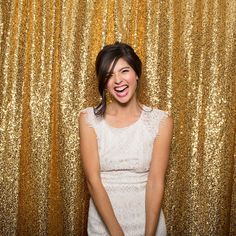 a woman standing in front of a gold backdrop