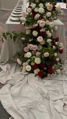 the table is covered with white and red flowers on it's sides, along with other tables in the background