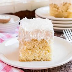 a slice of coconut cake on a plate with a fork and bowl in the background