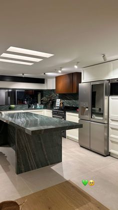 a kitchen with marble counter tops and stainless steel refrigerators, along with an island in the middle