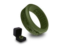 a green ring with an intricate design on it and a small black object next to it