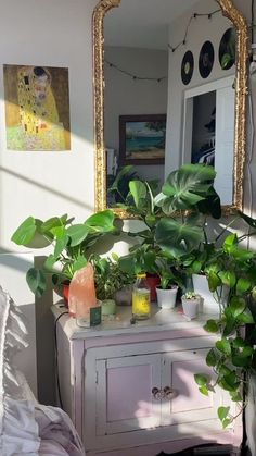 there is a mirror and some plants on the dresser in this room with white walls