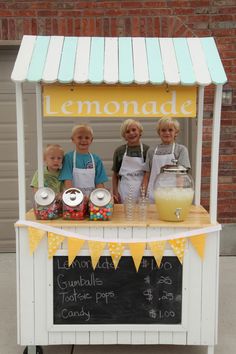 three children standing behind a lemonade stand