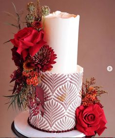 a three tiered white cake with red flowers on top