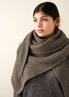 a woman wearing a gray sweater and a brown shawl is looking at the camera