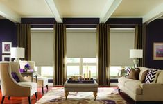 a living room filled with lots of furniture and windows covered in shades of brown, beige and white