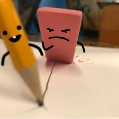 a pencil and eraser sitting next to each other on a table with an angry face drawn on it