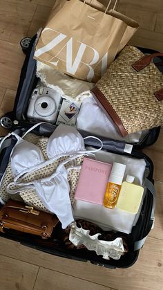 an open suitcase filled with personal items on top of a hard wood floored floor