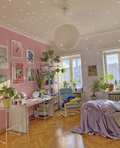 a bedroom with pink walls and lots of potted plants on the windowsills