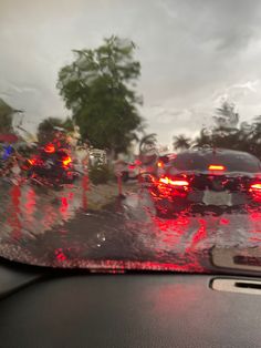 the rear view mirror shows cars driving on a wet road