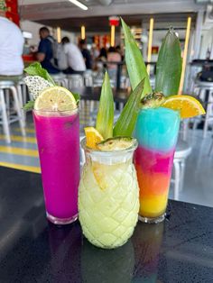 three different colored drinks sitting on top of a table